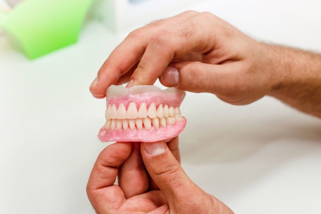Manos sosteniendo prótesis dental hecha en Laboratorio de Prótesis Dentales en Almería