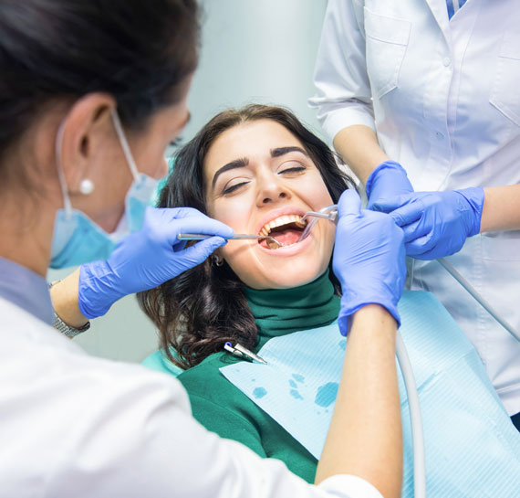 Paciente joven siendo atendida por dos dentistas
