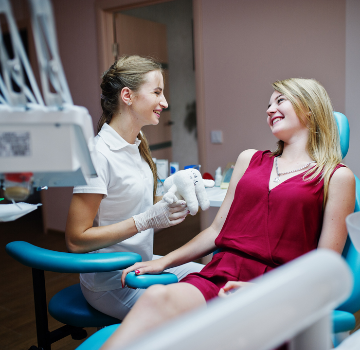 Joven dentista atiendo paciente mujer en consultorio dental