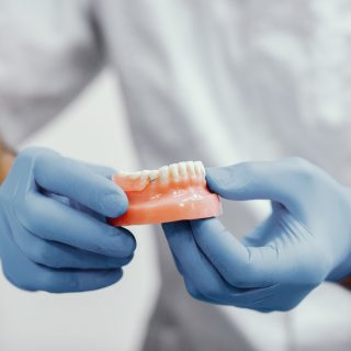 Dentista sosteniendo en su mano prótesis dental en Laboratorio de Prótesis Dentales en Almería