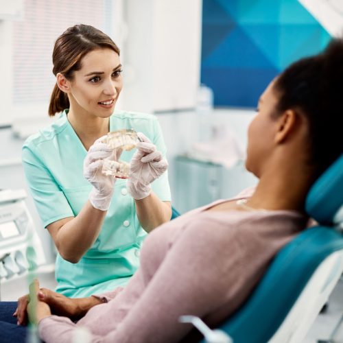 Joven ortodoncista hablando con paciente acerca de una prótesis mixta